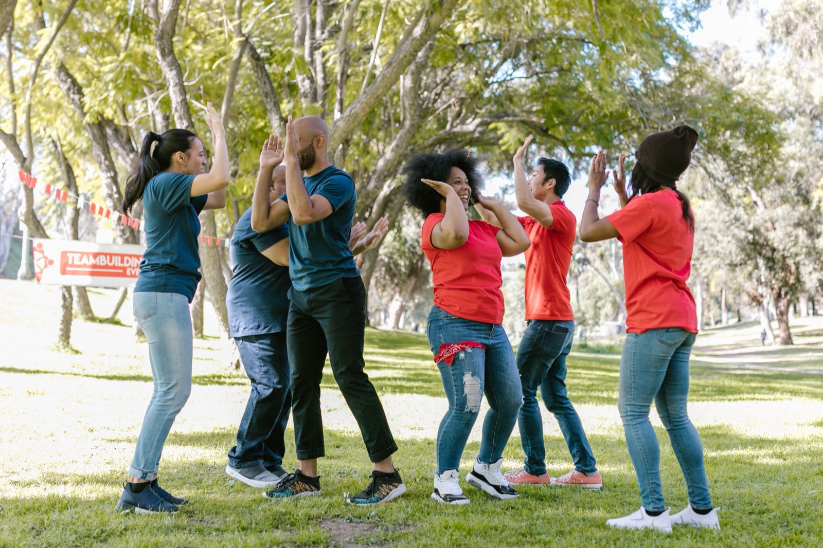 A mixed team celebrating at a station on grass, arms up.