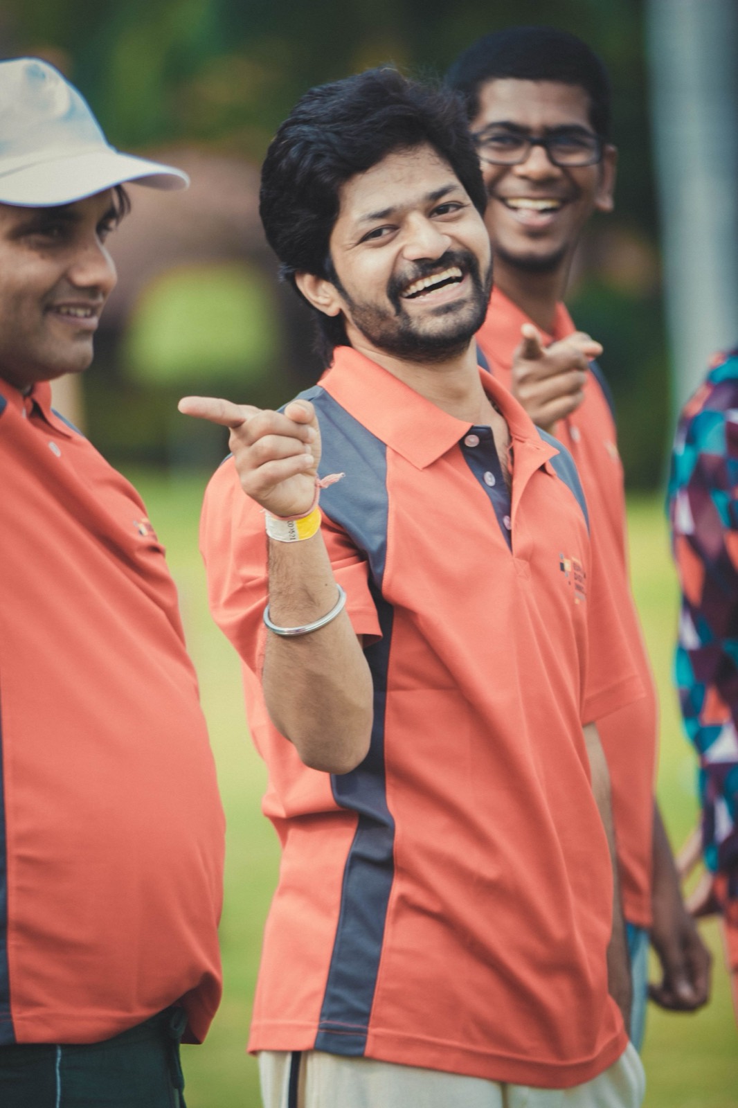 Three players in team shirts laughing on the boundary between fixtures.