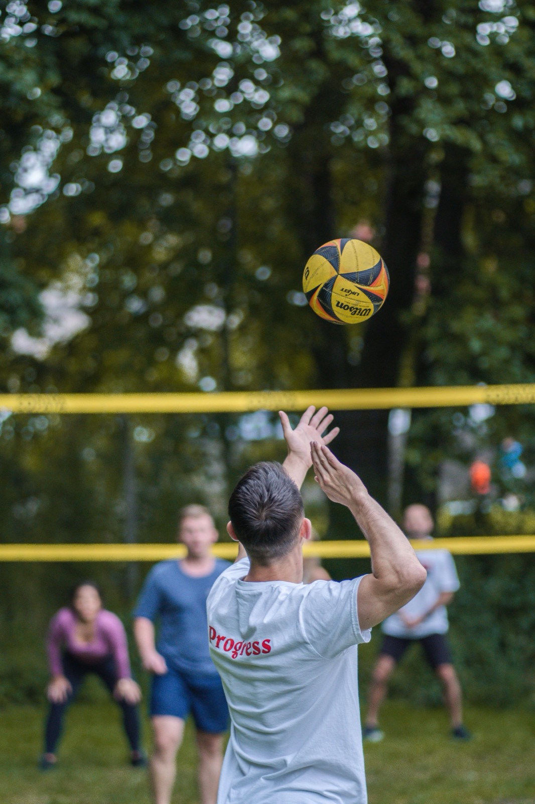 A player serving a volleyball on an outdoor court.